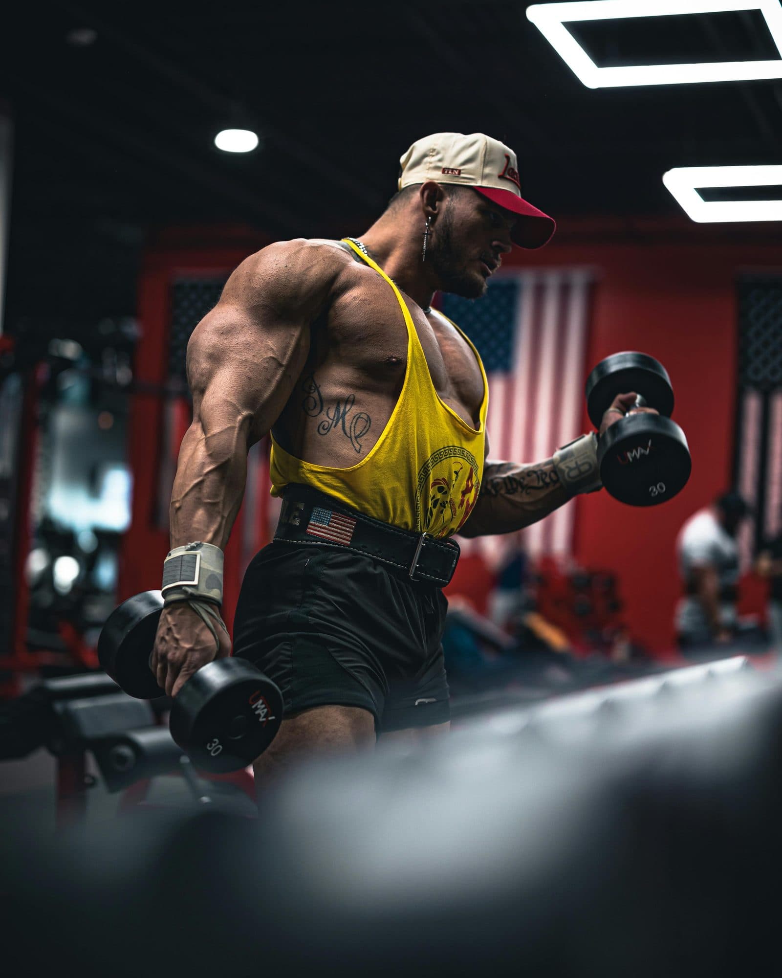 Vascular bodybuilder in a gym performing a dumbbell curl — the patient population this page serves: men running supraphysiologic protocols who need honest medical work
