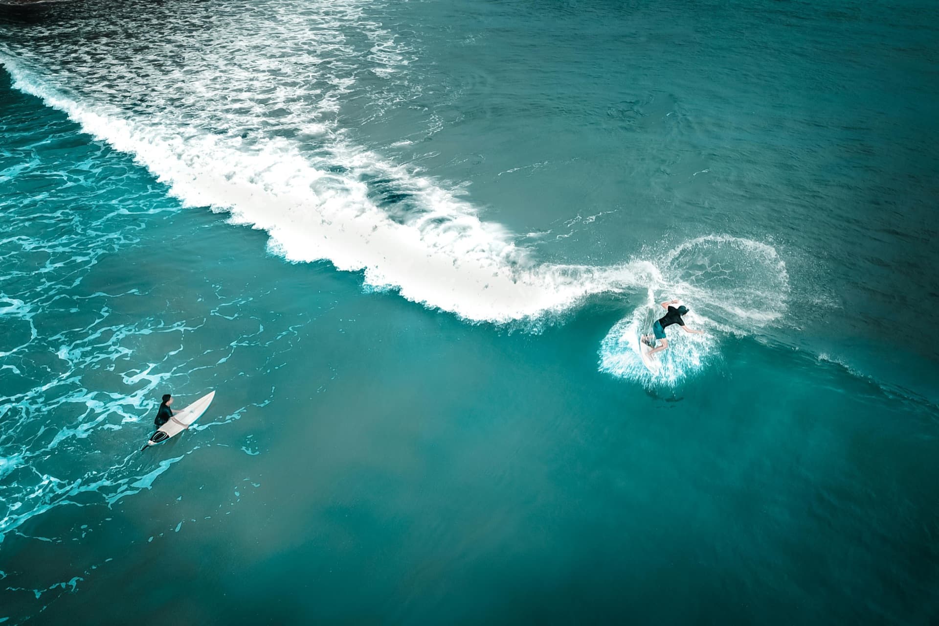 Aerial view of two surfers in turquoise Pacific water — the active Orange County coastal lifestyle Castellano patients live in
