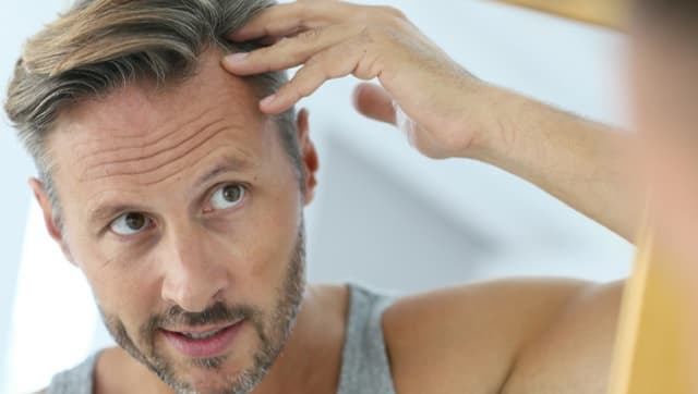 A man checking his hairline in the mirror